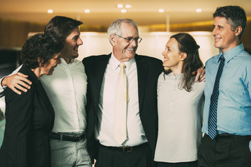 Smiling Senior Business Leader Embracing Coworkers