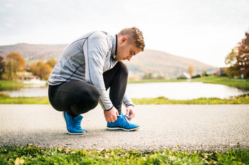 Handsome young runner tying shoelaces.