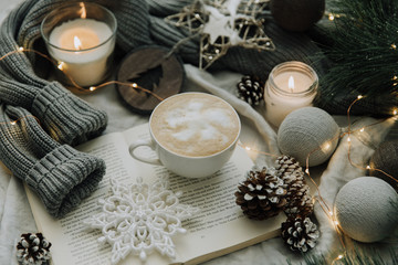 Coffee cup, book, Christmas decorations and warm knitted sweater. Cozy winter home morning holiday.
