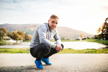Handsome young runner squatting down.