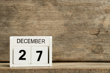 White block calendar present date 27 and month December on wood background