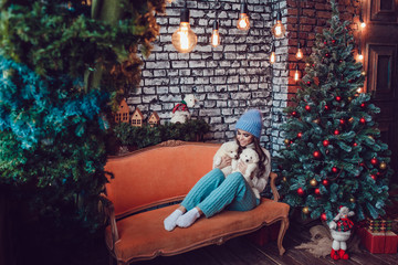 Beautiful woman with cute puppies sitting near Christmas tree. New Year.
