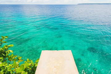 White springboard and green leaves on beautiful blue sea background.