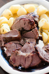 Close up of serving platter with slow roasted lamb shoulder with herbs and oven-roasted potatoes in dark jus served as Sunday roast on easter Sunday