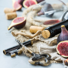 Fototapeta na wymiar Bottle, corkscrew, glass of red wine, figs on a table