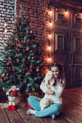 Beautiful woman with cute puppies sitting near Christmas tree. New Year.