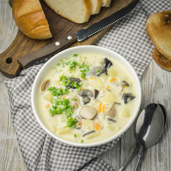 Homemade chicken spinach mushroom soup and sliced bread on white wooden background. Top view, space for text.