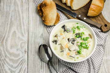 Wild rice creamy mushroom soup and toasted bread on white wooden background. Top view, space for text.