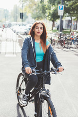 Fototapeta na wymiar young woman mixed race outdoors riding bicycle looking camera smiling - green lifestyle, sportive concept
