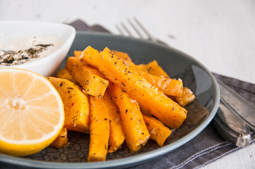 Snack. Pumpkin pieces baked in spices on a plate with cream sauce
