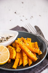 Snack. Pumpkin pieces baked in spices on a plate with cream sauce