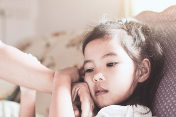 Cute asian child girl sickness and mother hand touch her face to check temperature with love and care