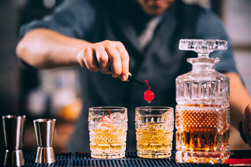 bartender preparing and lining crystal whisekey glasses for alcoholic drinks on bar