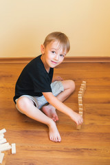 Cute boy playing on a floor with wooden blocks. Developing toys.