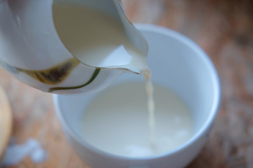 Pouring fresh milk into white cup
