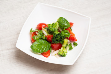 Salad from tomatoes, broccoli, basil, onions with spices