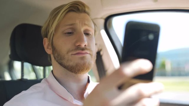 Man scrolling and checking smartphone while in a car and yawns