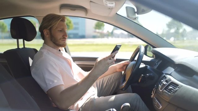 Man scrolling and checking smartphone while in a car and yawns