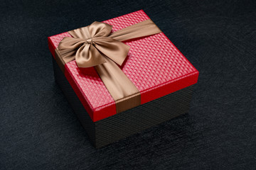 red gift box with brown bow on dark background
