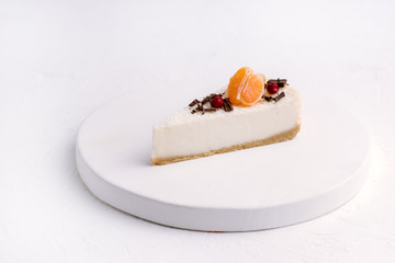 Slice of Cheesecake Decorated with Citrus and Berries WoodenTray White Background