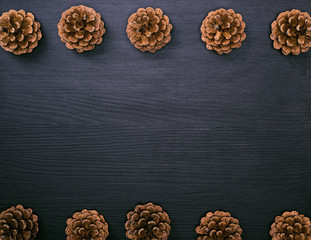 brown pine cones on a black wooden background
