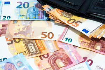 Pile of various kinds euro banknotes with black leather wallet use for money or currency background and financial concepts.
