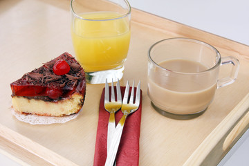 served romantic breakfast for valentine: morning cup of brewed coffee with milk, glass of orange juice and delicious cherry cheese cakes on coffee table