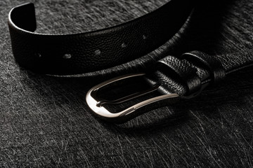 steel hook and the end of elegant leather belt for men on a dark background