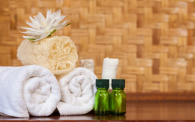 Obraz na płótnie Canvas Herbal compress, towel, lotus flower and luffa scrub on wooden table, spa and wellness concept