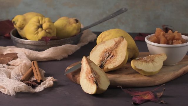 Quince fruits and marmelade in a ceramic bowl on table top.