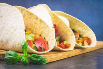 Traditional Mexican tacos with meat and vegetables on wooden background.