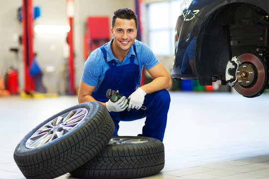 Car mechanic in workshop changing tires
