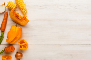 Border of various yellow vegetables on white wood