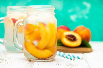 Homemade iced lemonade with ripe peaches. Fresh peach ice tea in a mason jar.