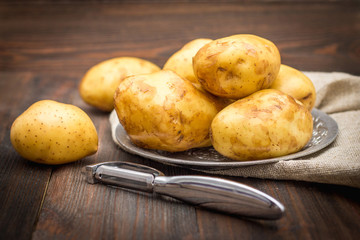 Raw potatoes on a brown wooden background.