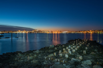 Night photo view of Portland Maine, USA. The smooth water, the city's buildings on the other shore are reflected in the water of the bay.
