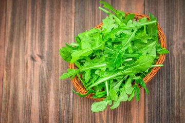Fresh juicy leaves of arugula on a brown wooden table.