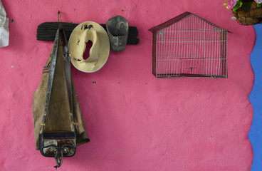 Old rural hanger with bird cage, hat, old stirrup and leather items