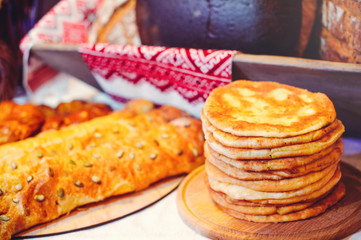 pile of air pancakes on a wooden dinette, a traditional food family. golden pancakes, pies in the background