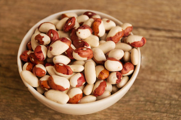 Сolorful kidney beans in the bowl on a wooden table. Close up