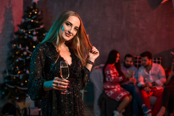 Beautiful young woman with glass of champagne at Christmas party