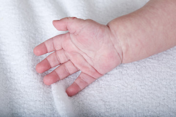 Beautiful baby hand on white soft blanket