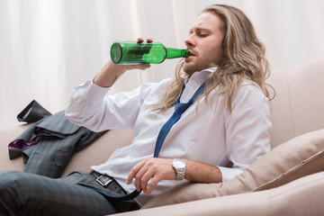 Man lying on a sofa and drinking beer