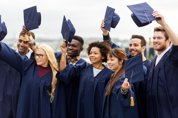 happy graduates or students waving mortar boards