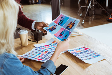 cropped shot of multicultural photographers choosing photos together at workplace in office