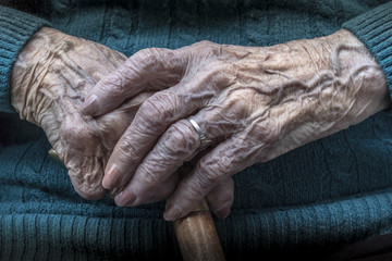 Manos de mujer anciana sosteniendo bastón de madera