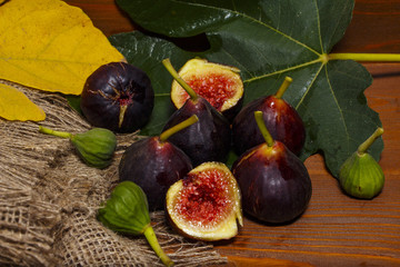 Ripe sweet figs with green leaves. Healthy Mediterranean fig figs. On a wooden board with burlap.
