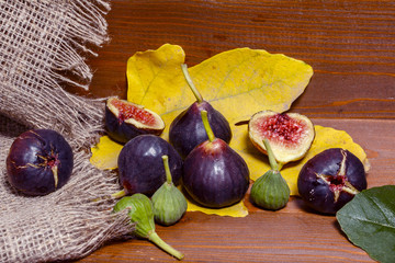 Ripe sweet figs with green leaves. Healthy Mediterranean fig figs. On a wooden board with burlap.