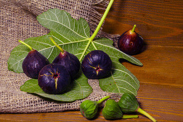 Ripe sweet figs with green leaves. Healthy Mediterranean fig figs. On a wooden board with burlap.