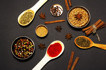 Assortment of spices in wooden spoons on a black background. View from above.
